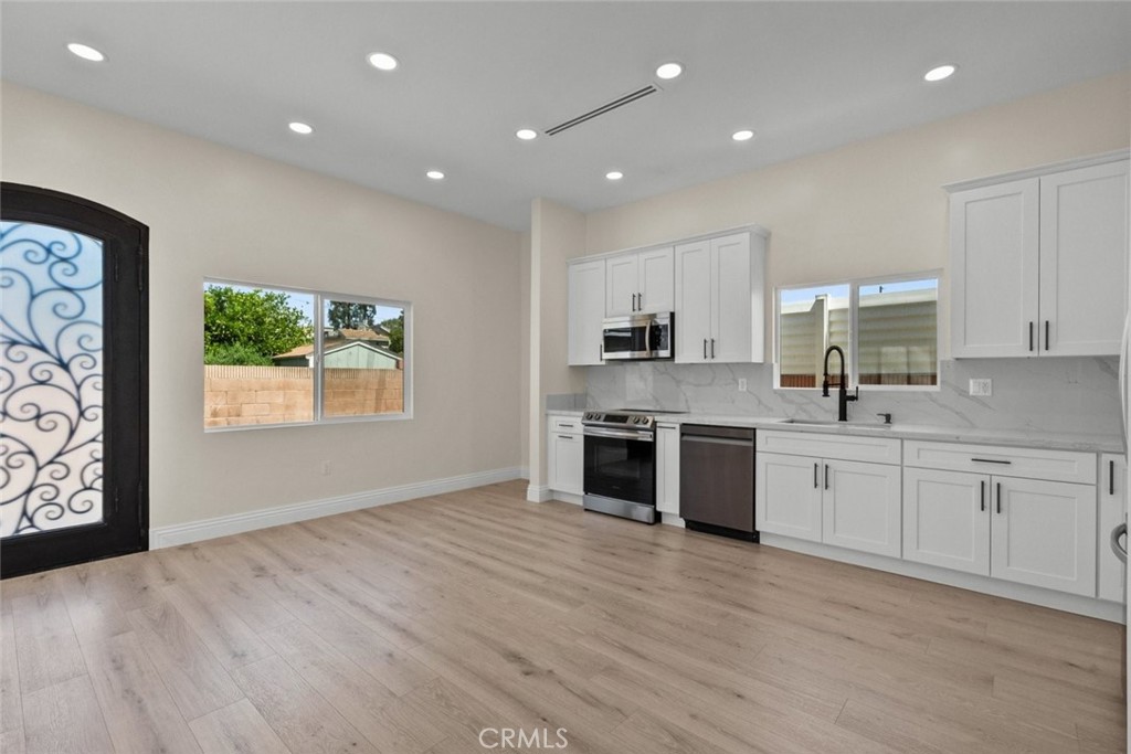 a large kitchen with stainless steel appliances granite countertop a stove a sink and white cabinets