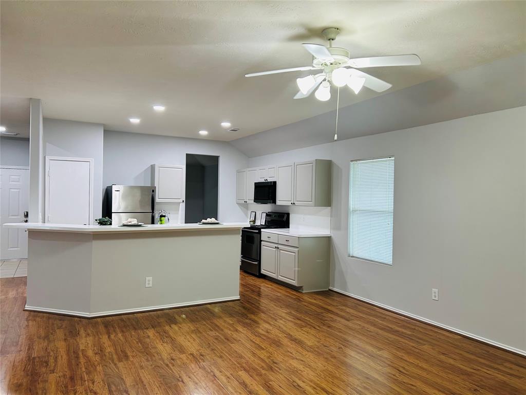 a living room with stainless steel appliances kitchen island granite countertop a sink cabinets and wooden floor