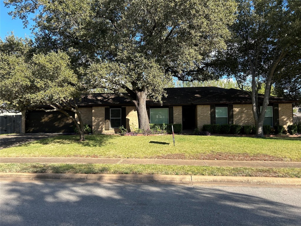 a view of a house with a yard and large tree