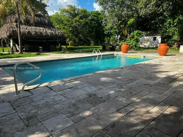 a view of a swimming pool with a patio and a yard