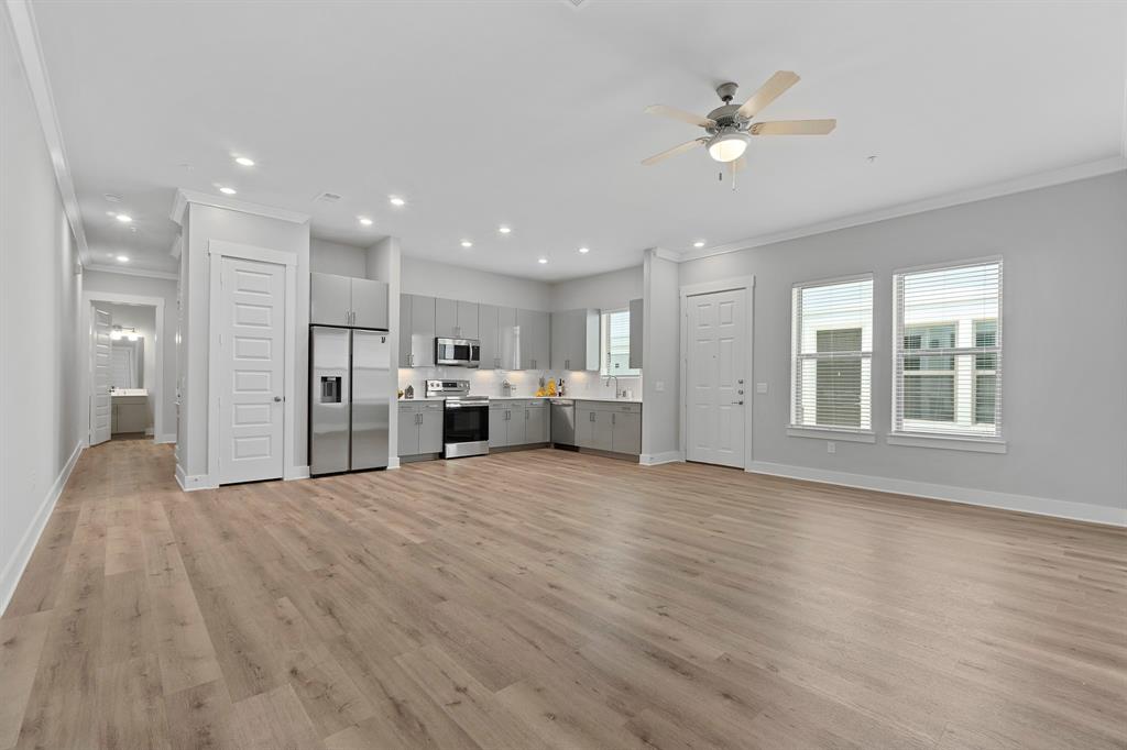 a view of an empty room with kitchen and window