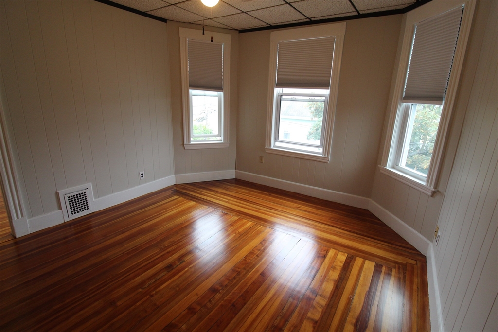 a view of empty room with wooden floor and fan