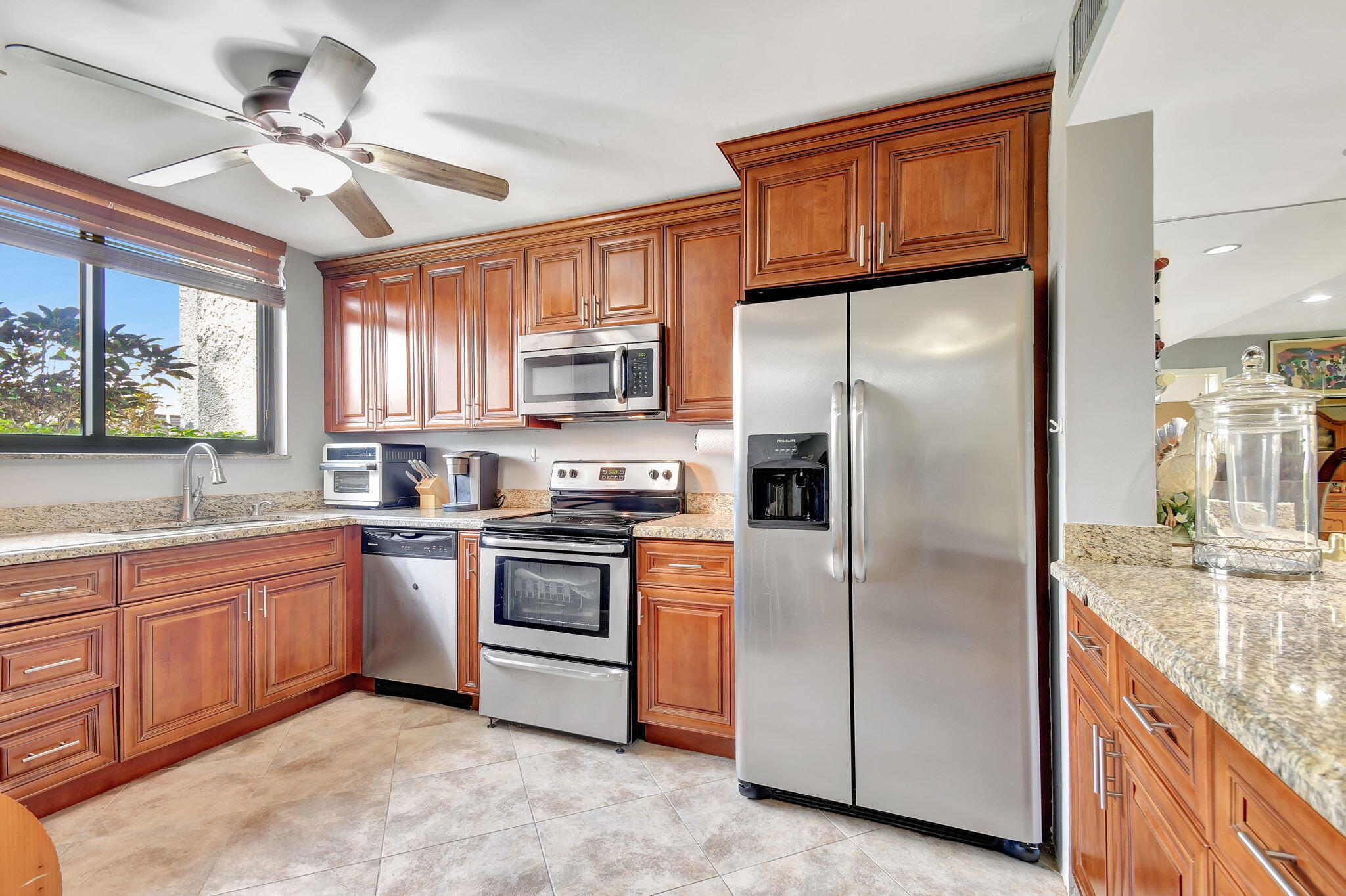 a kitchen with stainless steel appliances granite countertop a sink a stove a refrigerator with grey cabinets