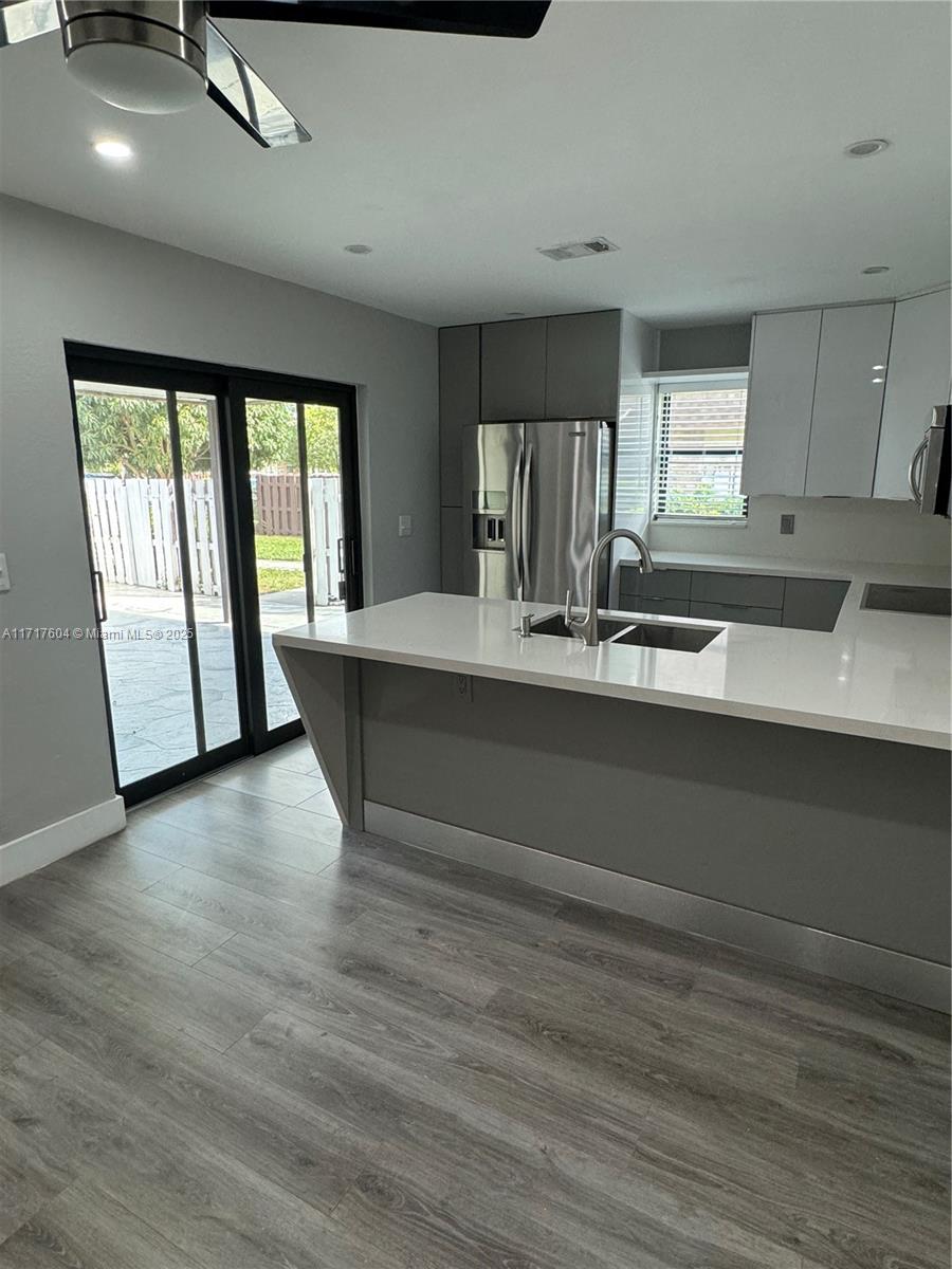 a view of kitchen with granite countertop a sink and dishwasher with wooden floor