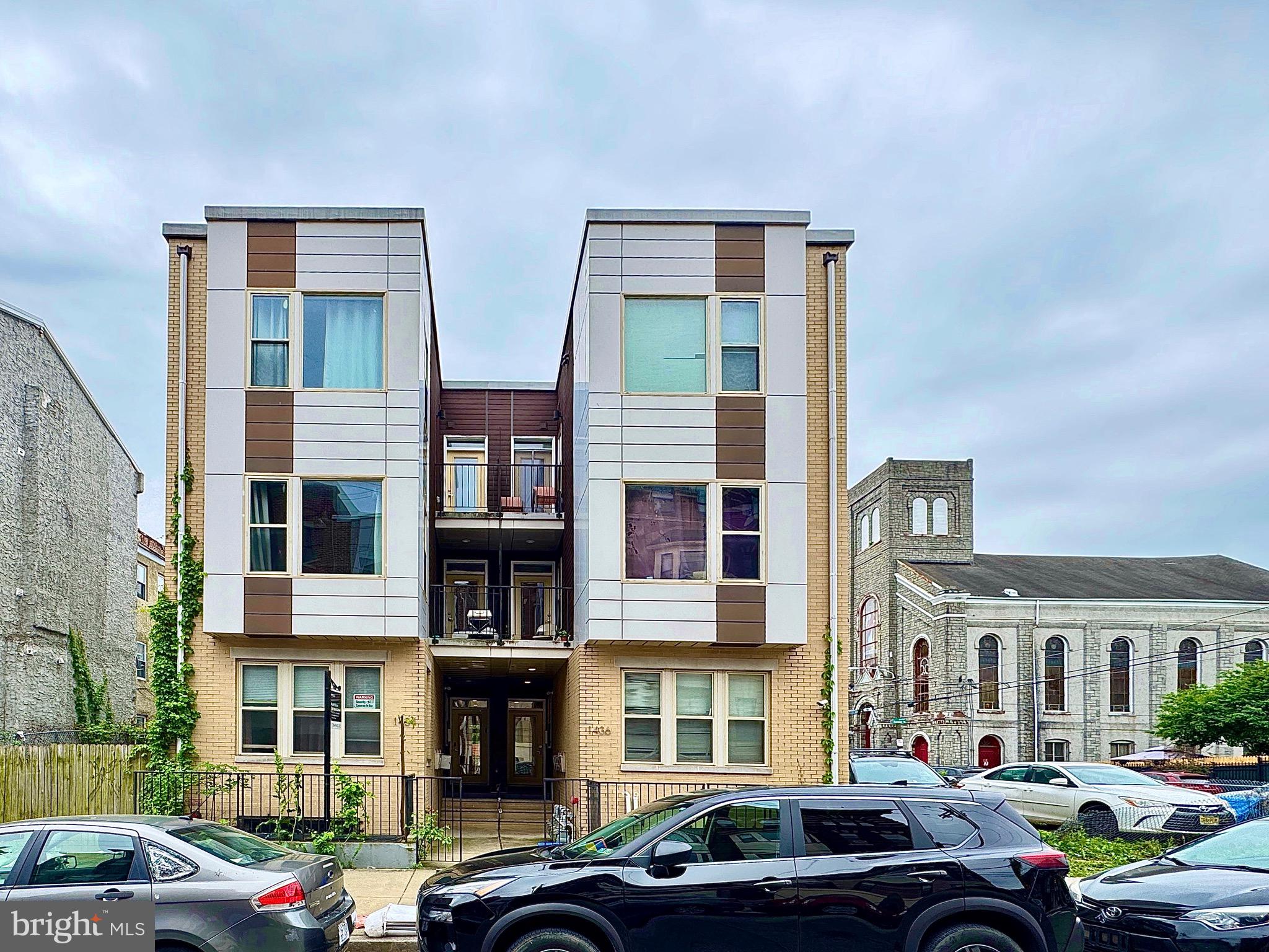 a front view of a building with cars parked