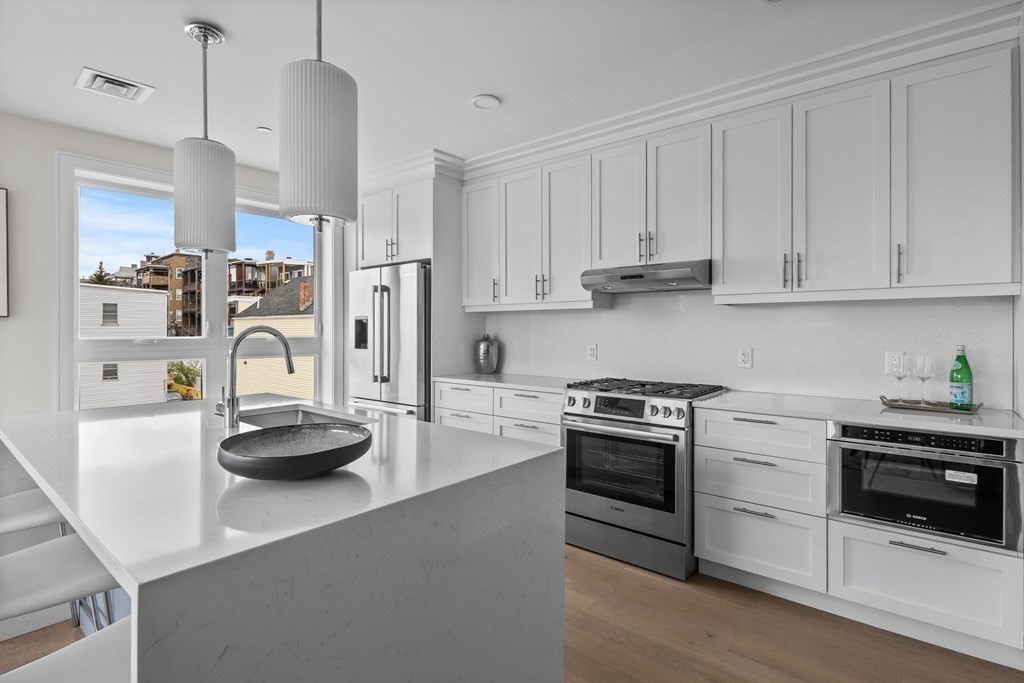 a kitchen with stainless steel appliances granite countertop a sink stove and white cabinets