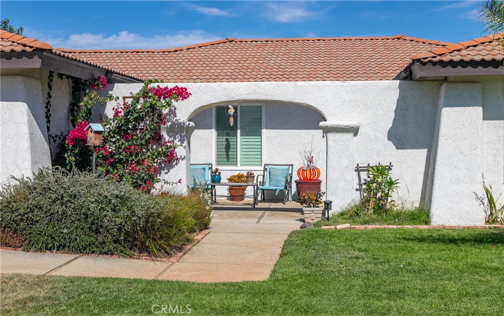 a view of a house with potted plants and a bench