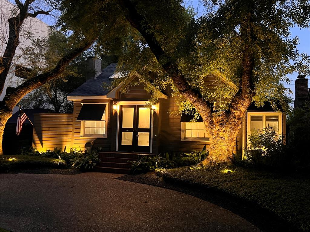 The front of the house features automated outdoor landscaping lights that beautifully illuminate the charming facade. Nestled under mature trees, the welcoming entrance is accented by the glow of strategically placed lighting, enhancing the curb appeal and providing a warm, inviting ambiance in the evenings.