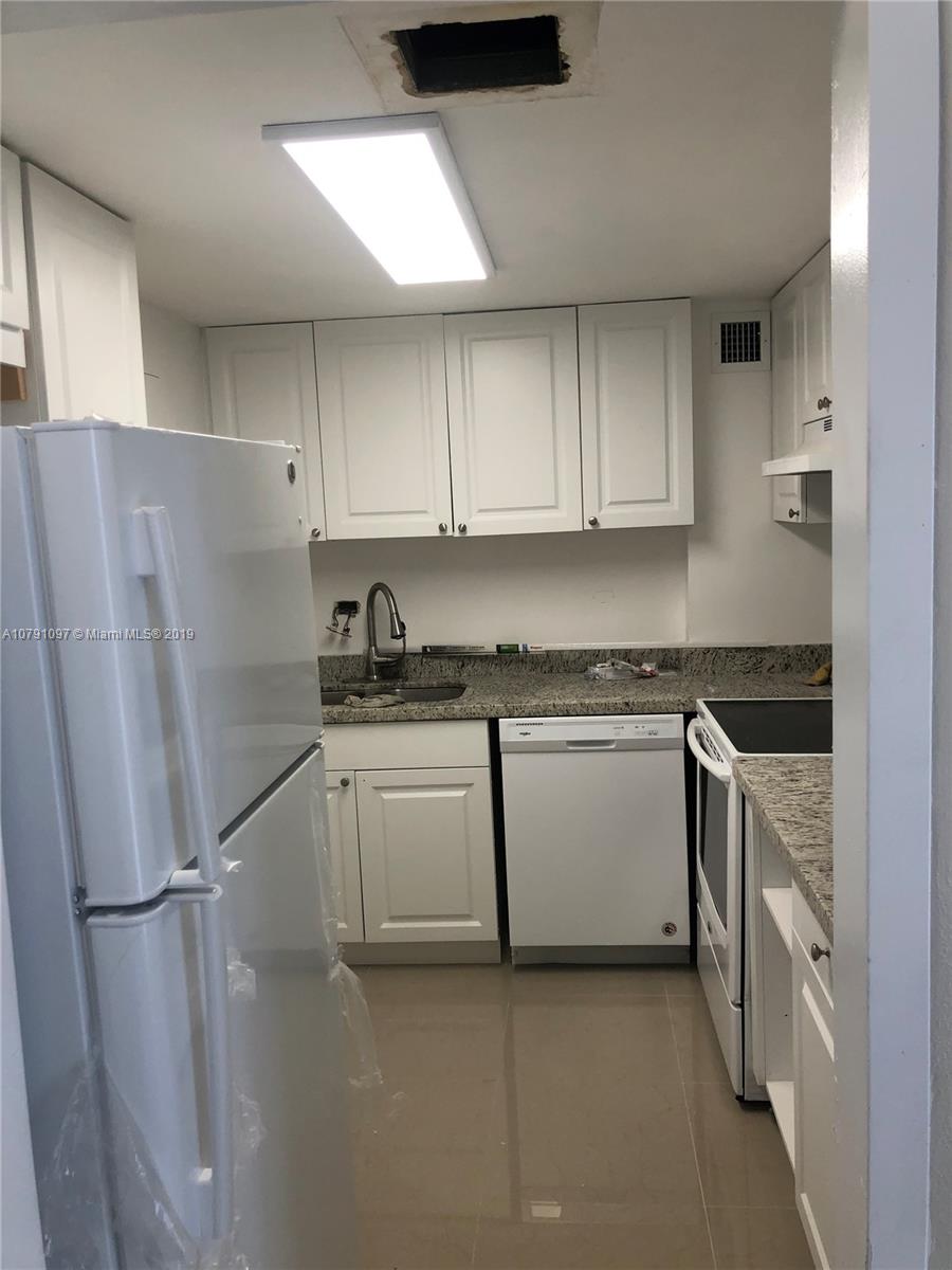 a kitchen with stainless steel appliances a refrigerator a sink and white cabinets