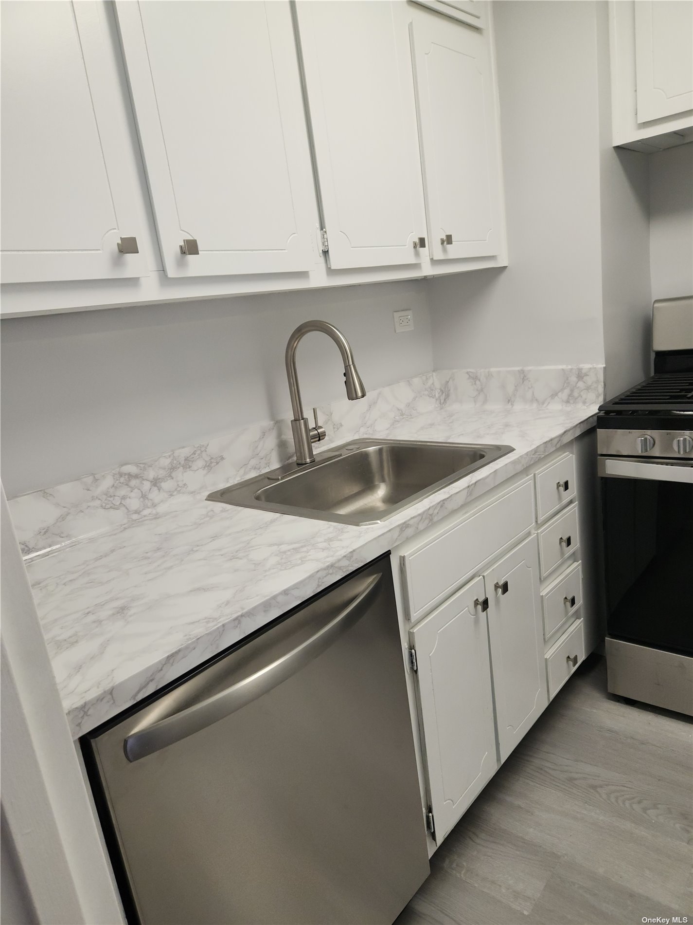 a kitchen with granite countertop white cabinets and a sink