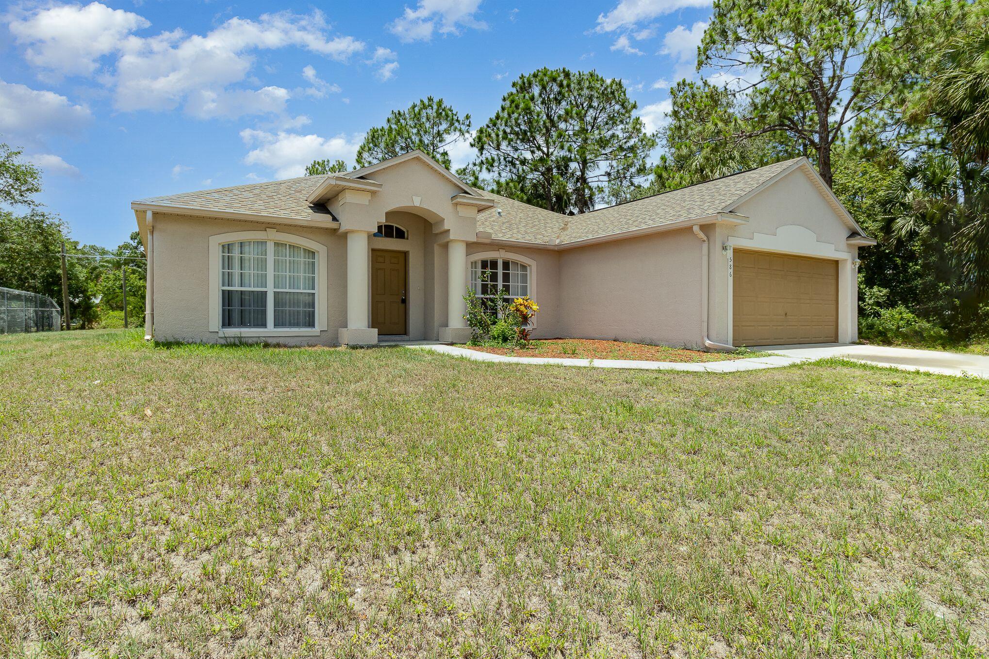 a front view of house with yard and trees in the background