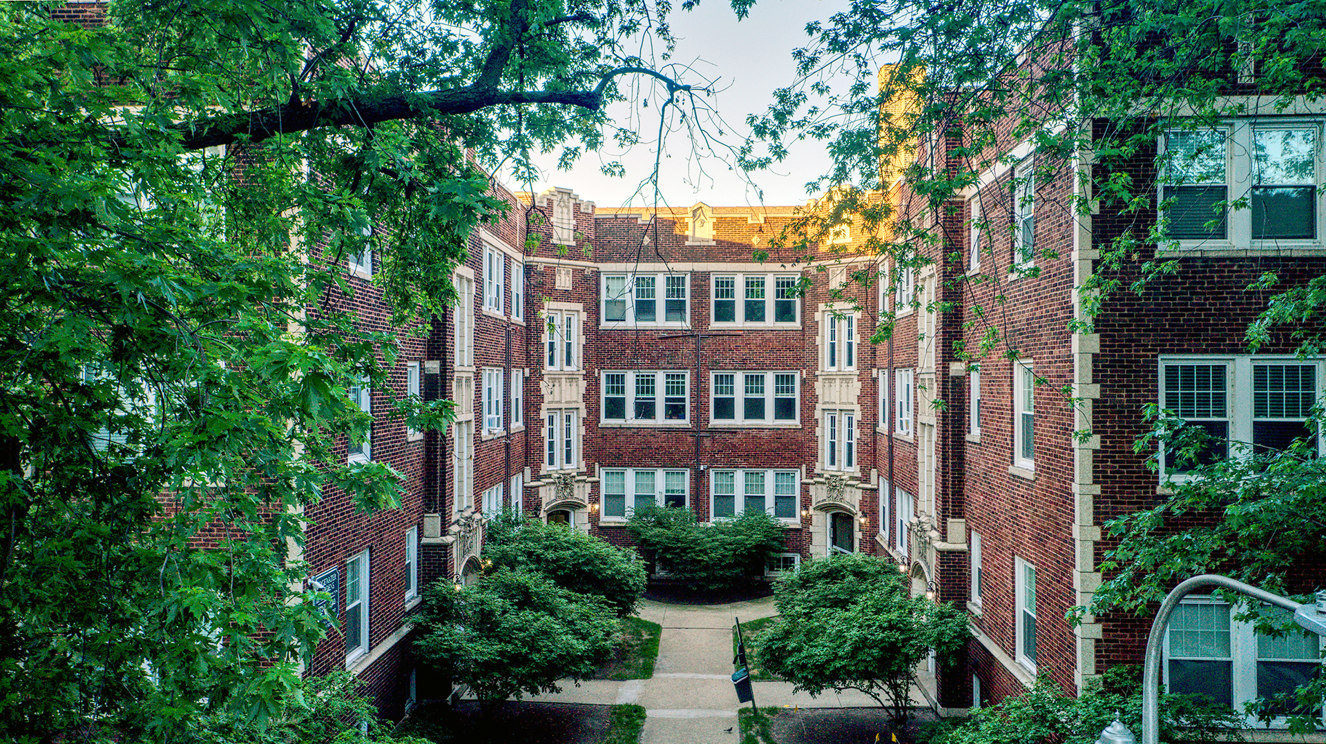 a front view of a residential apartment building with a yard and potted plants