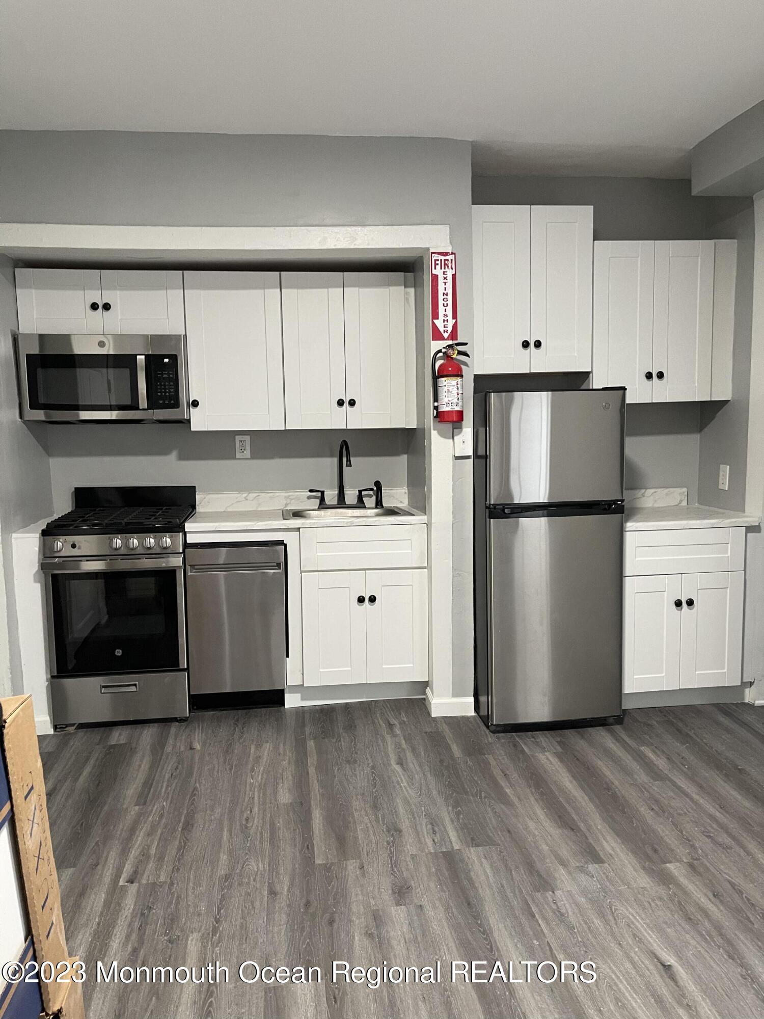 a kitchen with a refrigerator a stove top oven and white cabinets