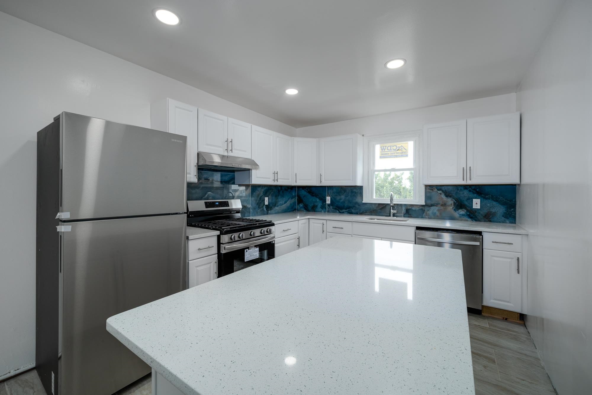 a kitchen with a refrigerator a stove top oven a sink and cabinets