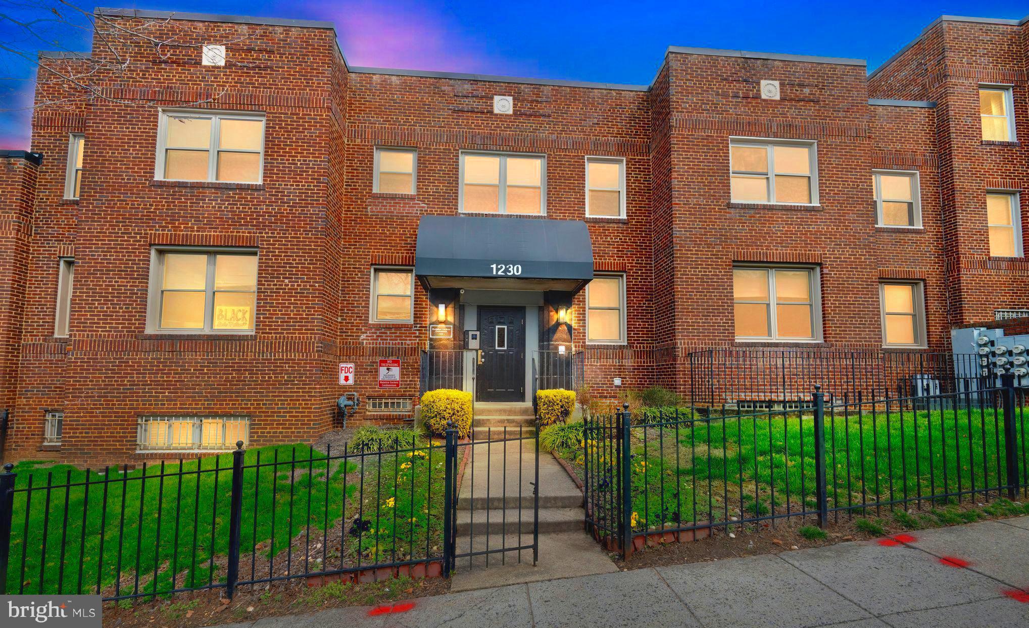 a front view of a brick building with a yard