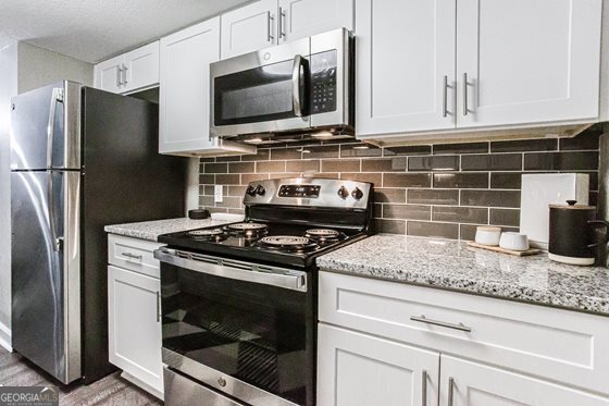 a kitchen with granite countertop a stove microwave and refrigerator