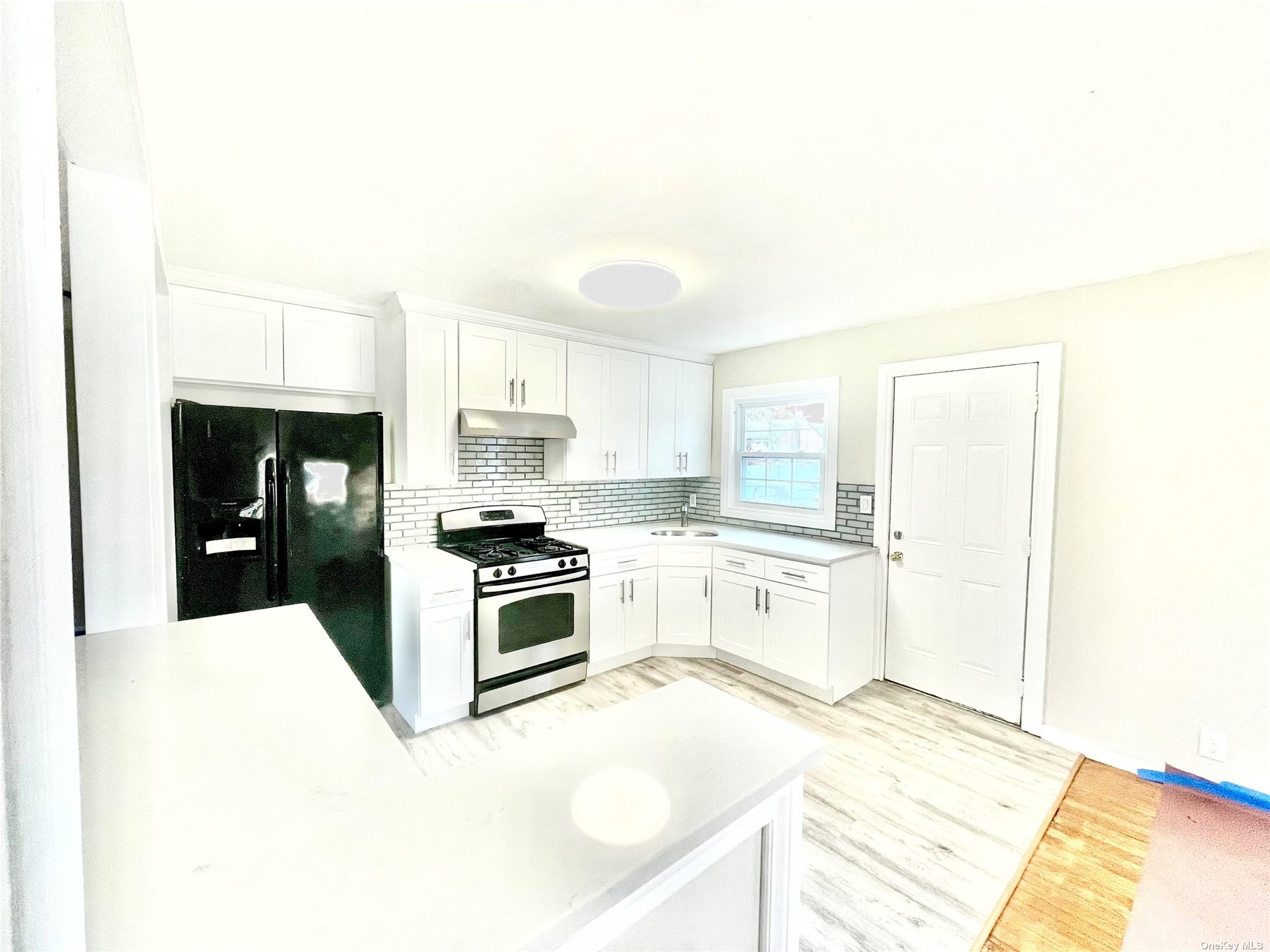 a large white kitchen with granite countertop a stove top oven