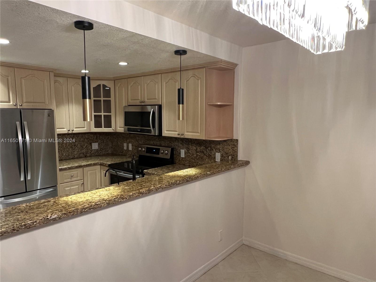 a kitchen with granite countertop a refrigerator and a sink