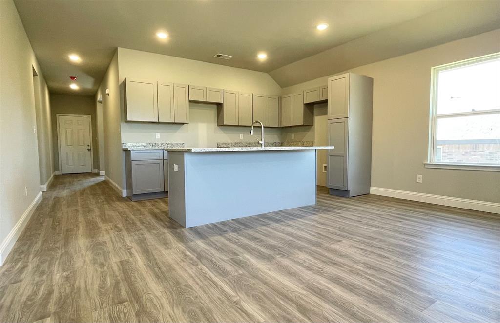 a view of kitchen with stainless steel appliances granite countertop a stove a sink dishwasher and a refrigerator with wooden floor