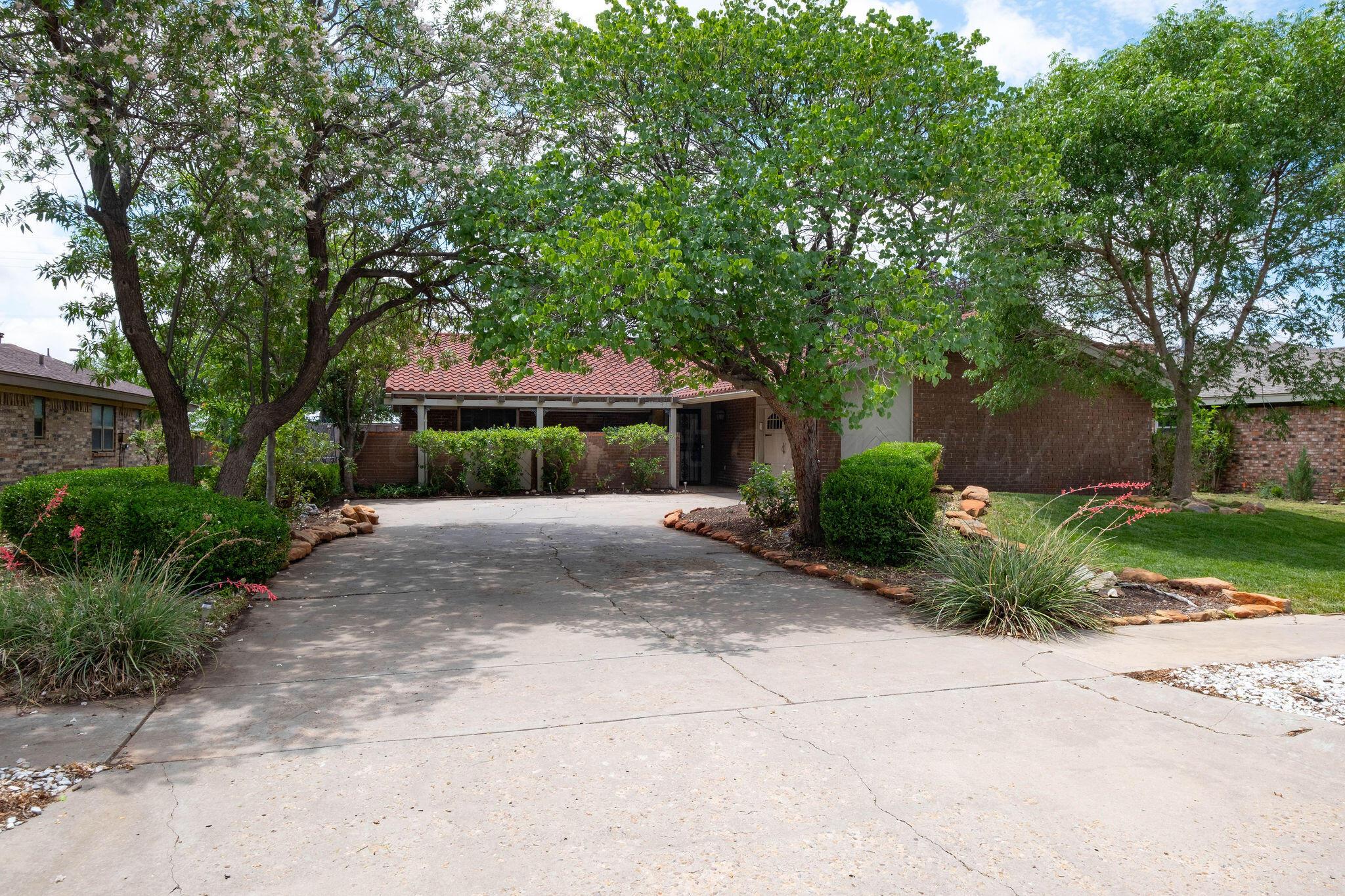 a front view of a house with garden and trees