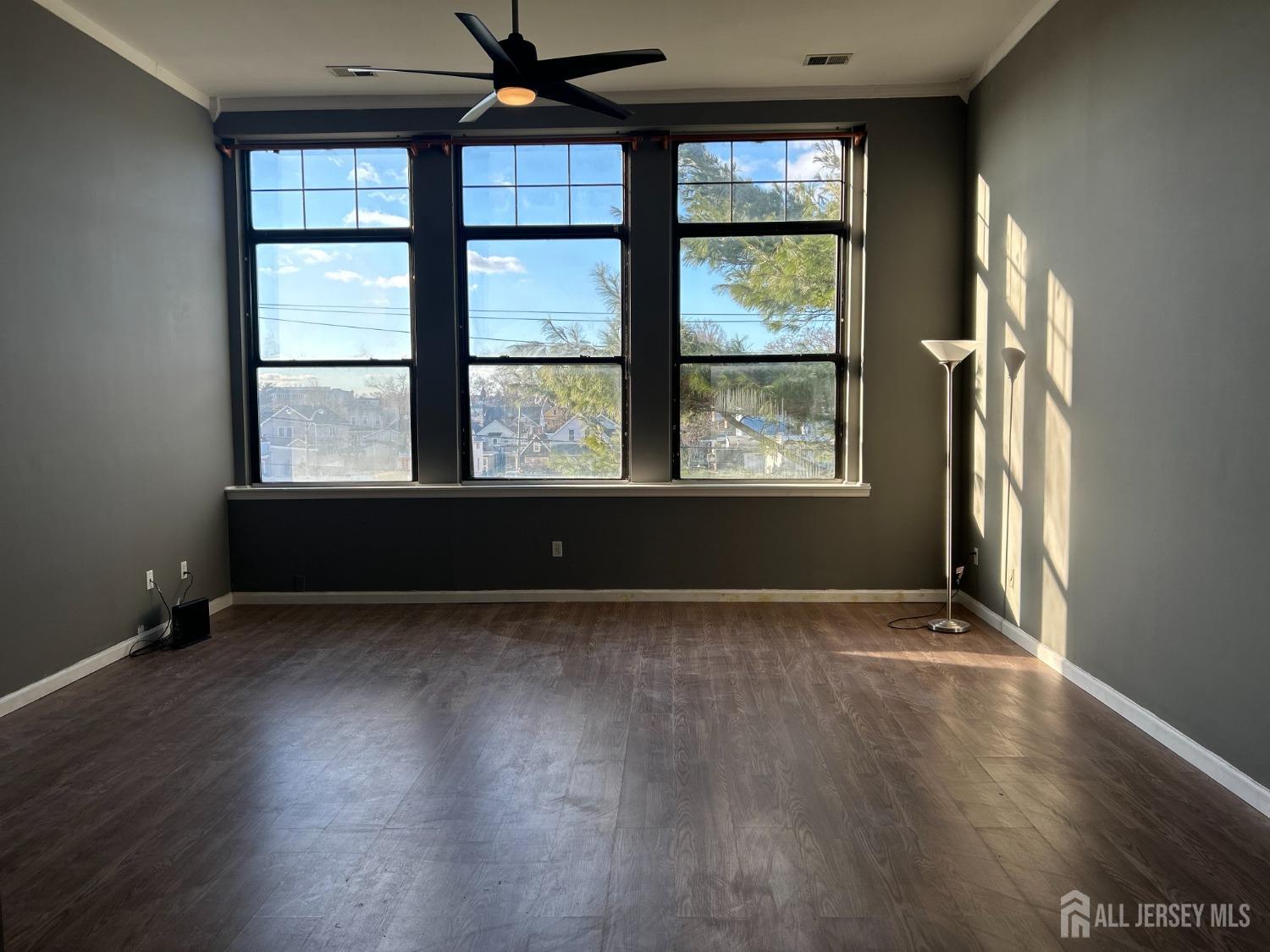 an empty room with wooden floor and windows