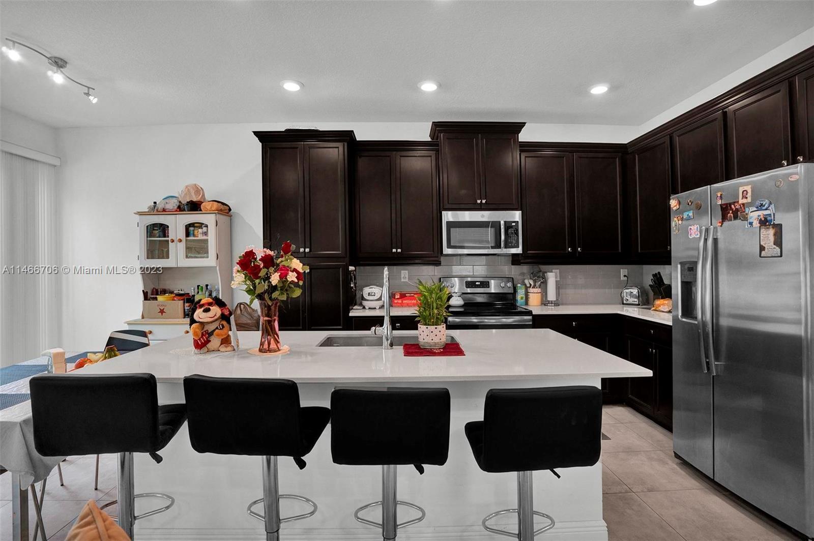 a kitchen with stainless steel appliances kitchen island granite countertop a refrigerator a sink and a stove