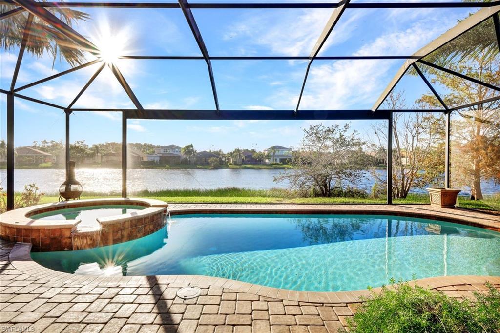 View of pool with an in ground hot tub, a water view, and glass enclosure