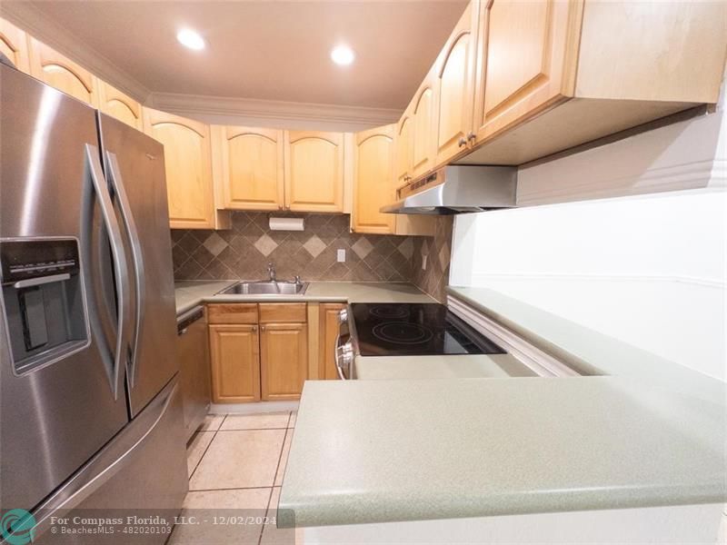 a kitchen with stainless steel appliances kitchen island granite countertop a refrigerator and a sink