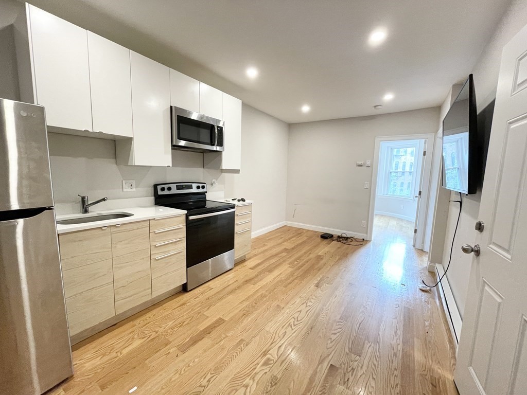 a kitchen with granite countertop a refrigerator stove top oven and sink