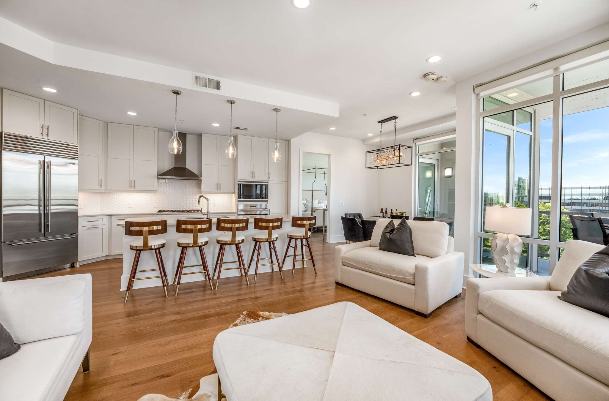 a living room with furniture kitchen view and a large window