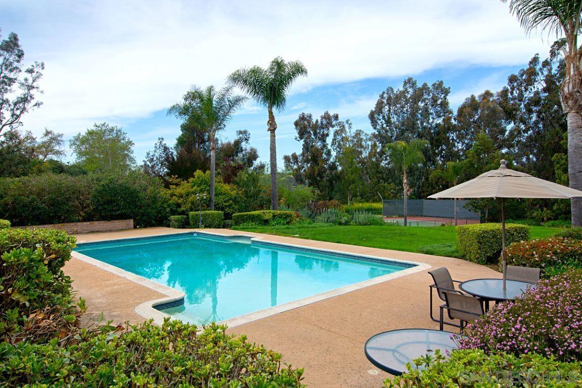 a view of pool with lawn chairs under an umbrella