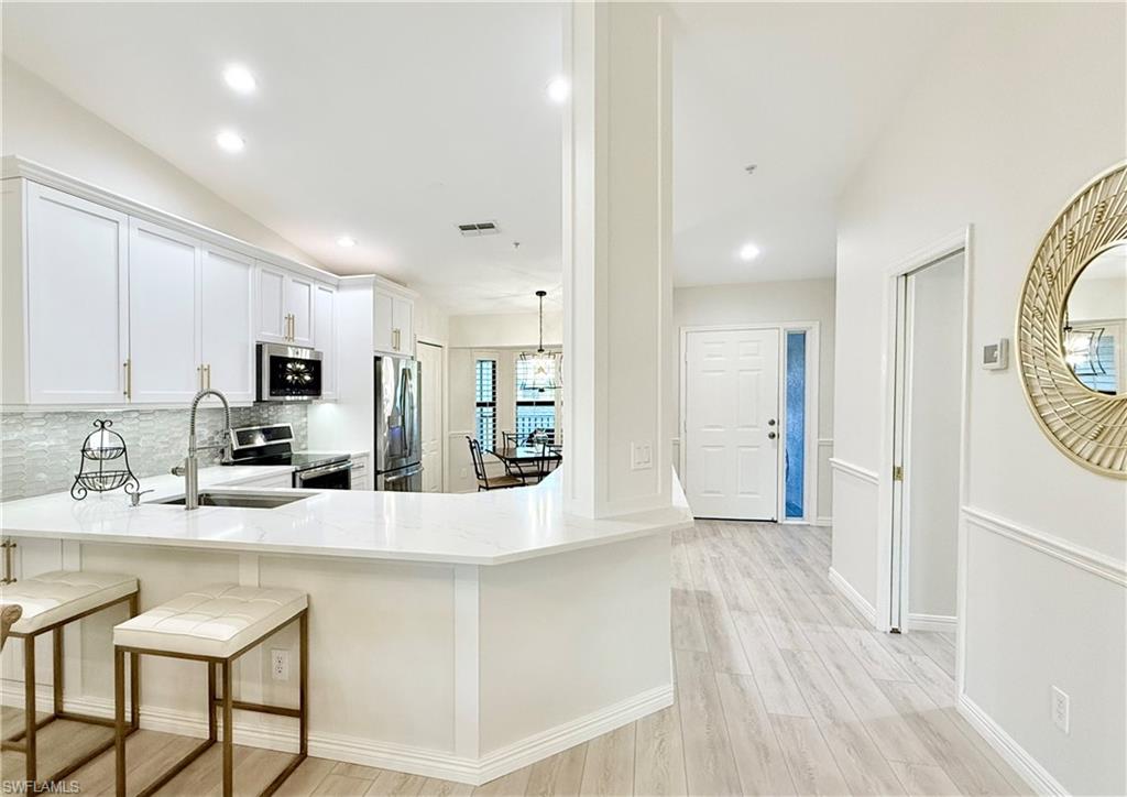 a large white kitchen with a refrigerator a sink dishwasher and a stove with wooden floor