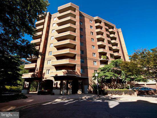 a front view of a building with street view and trees