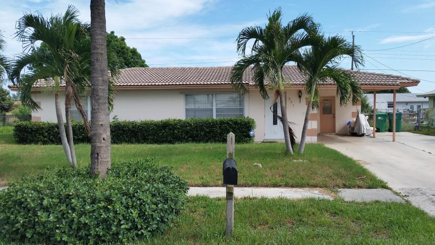 a view of a house with a yard and palm trees