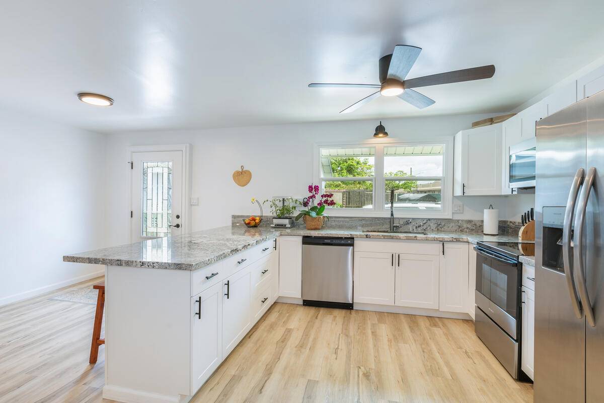 a kitchen with granite countertop stainless steel appliances a sink cabinets and a large window