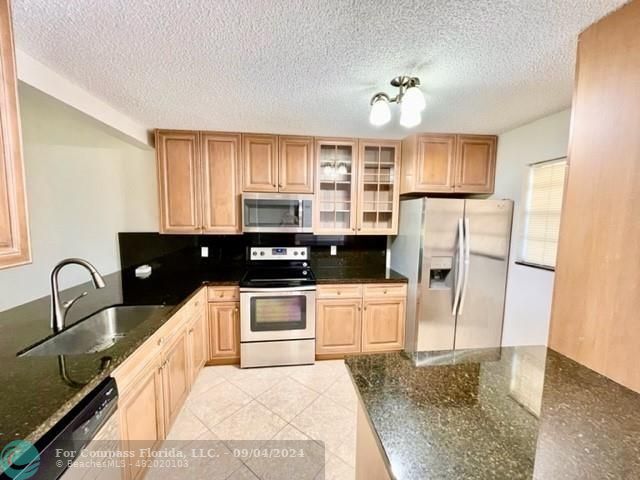 a kitchen with stainless steel appliances granite countertop a refrigerator a stove a sink and a microwave