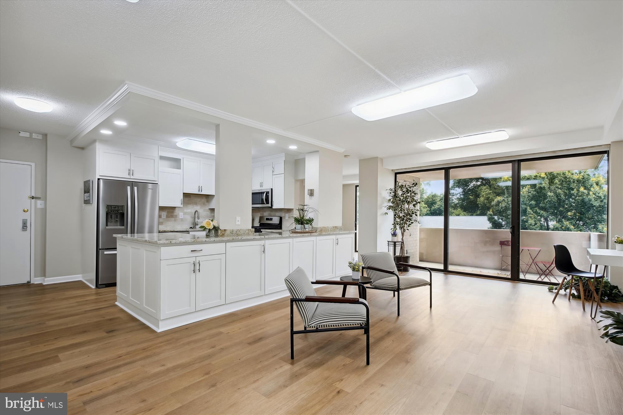 a kitchen with white cabinets stainless steel appliances and dining table with wooden floor