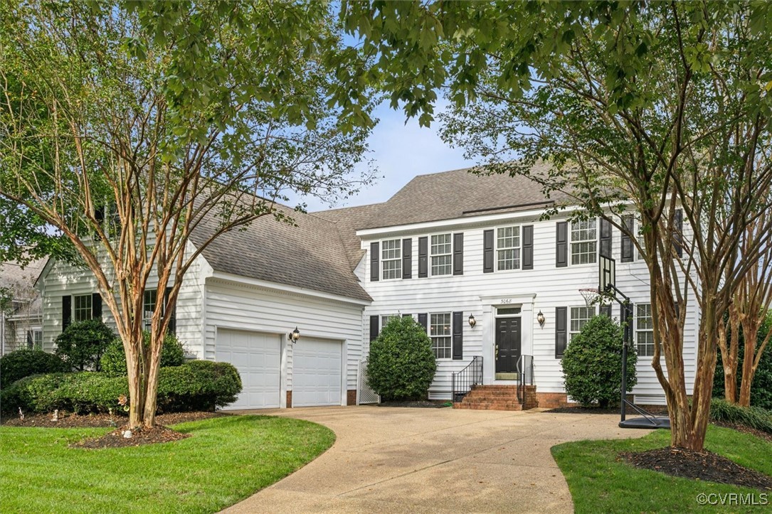 Colonial inspired home with a garage and a front y