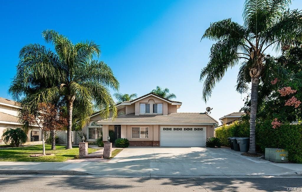 a view of a house with a yard and palm trees