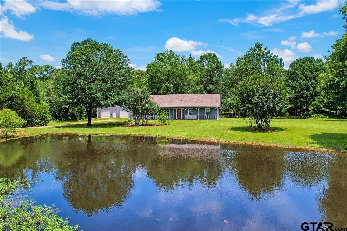 a view of a lake with a yard and large trees