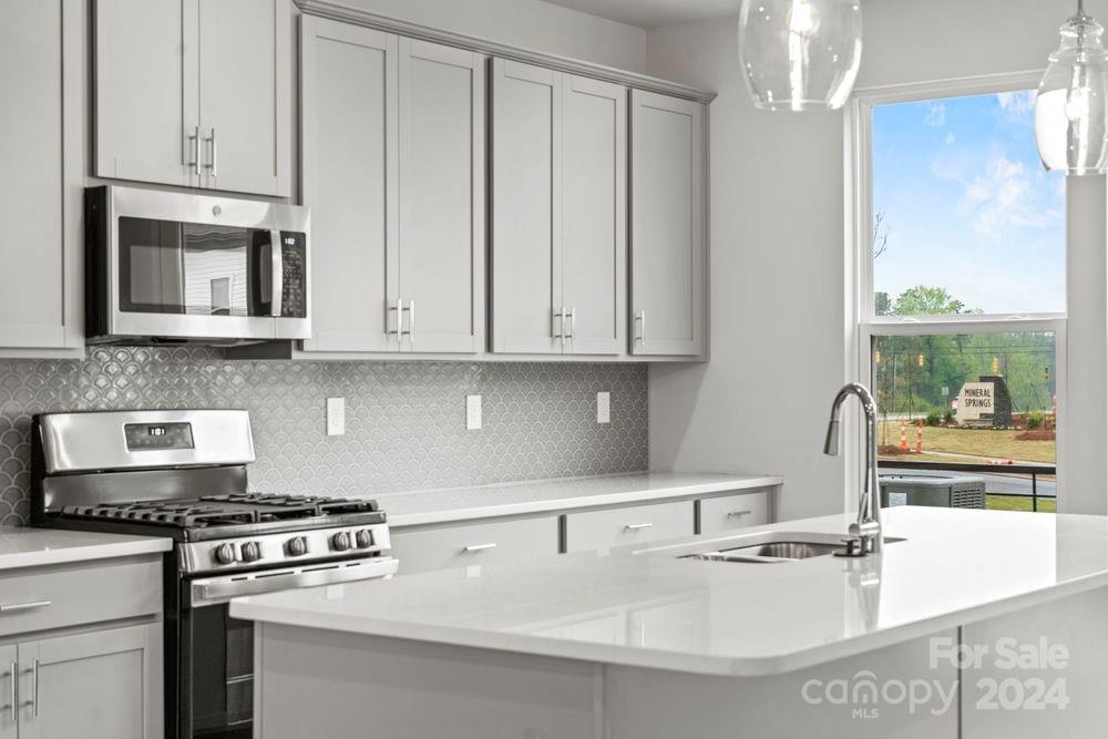 a kitchen with stainless steel appliances granite countertop a sink stove and cabinets