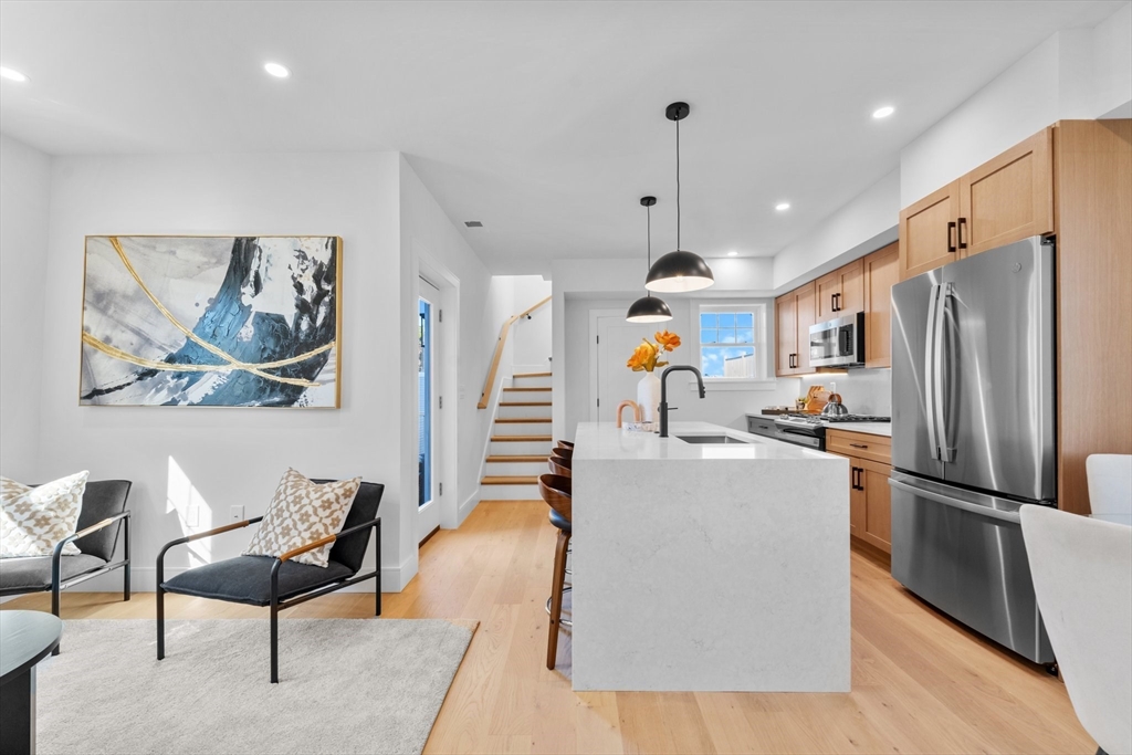 a living room with stainless steel appliances granite countertop furniture a fireplace a rug and a window