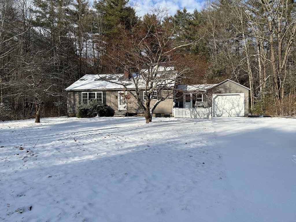 a front view of a house with large trees