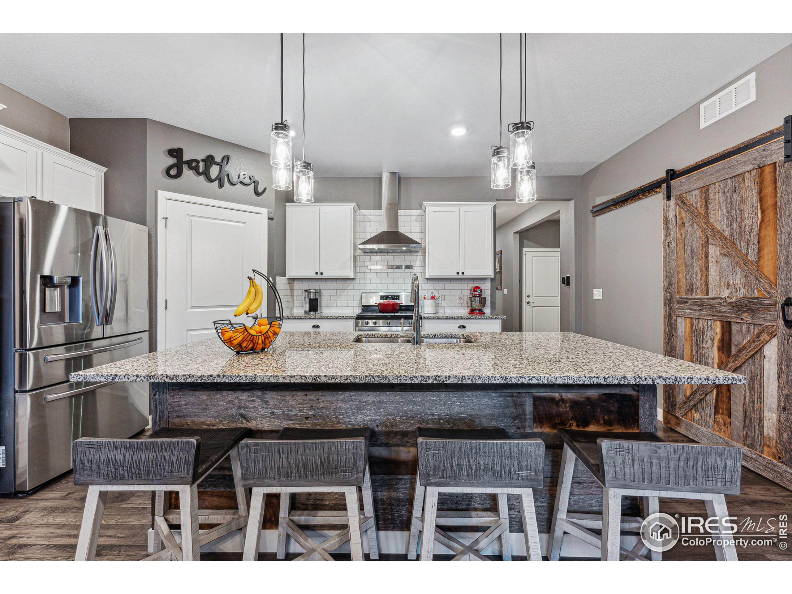 a kitchen with granite countertop a table chairs stove and refrigerator