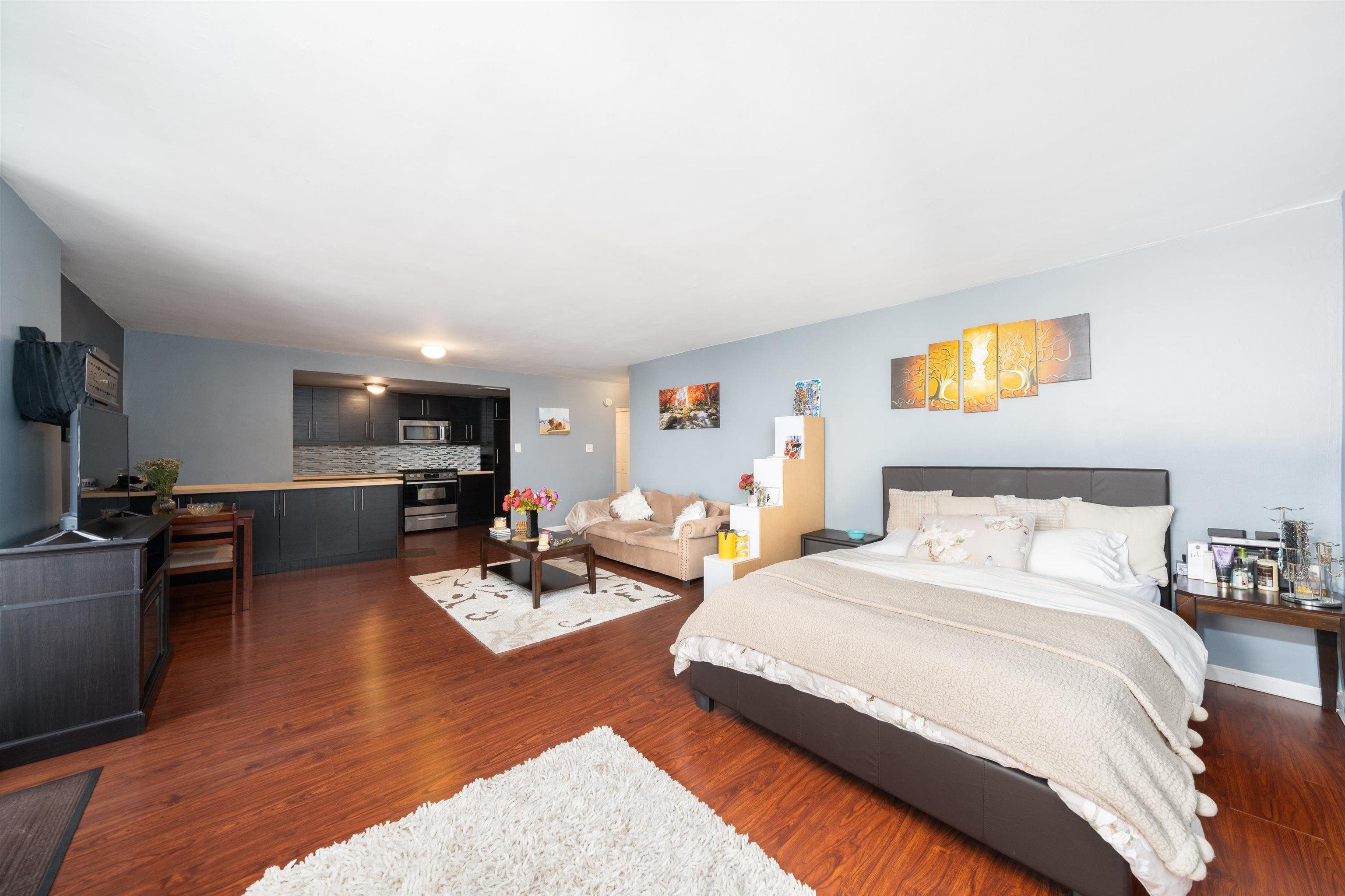 a bedroom with a bed a couch and a flat screen tv