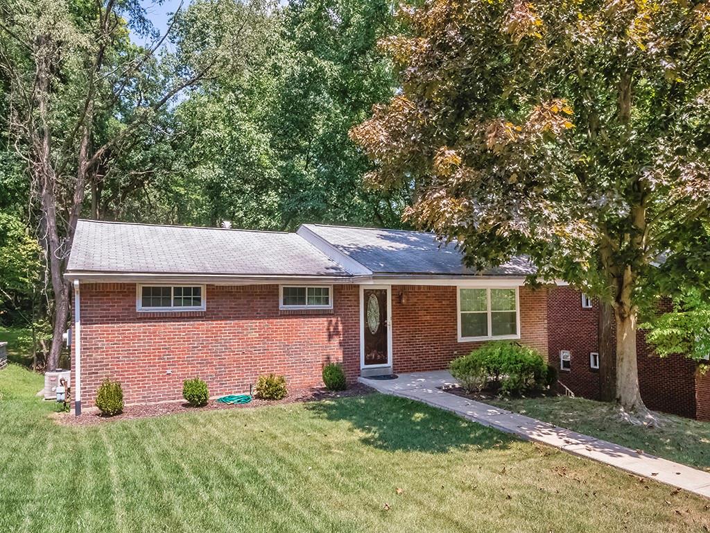 a front view of house with yard and trees all around