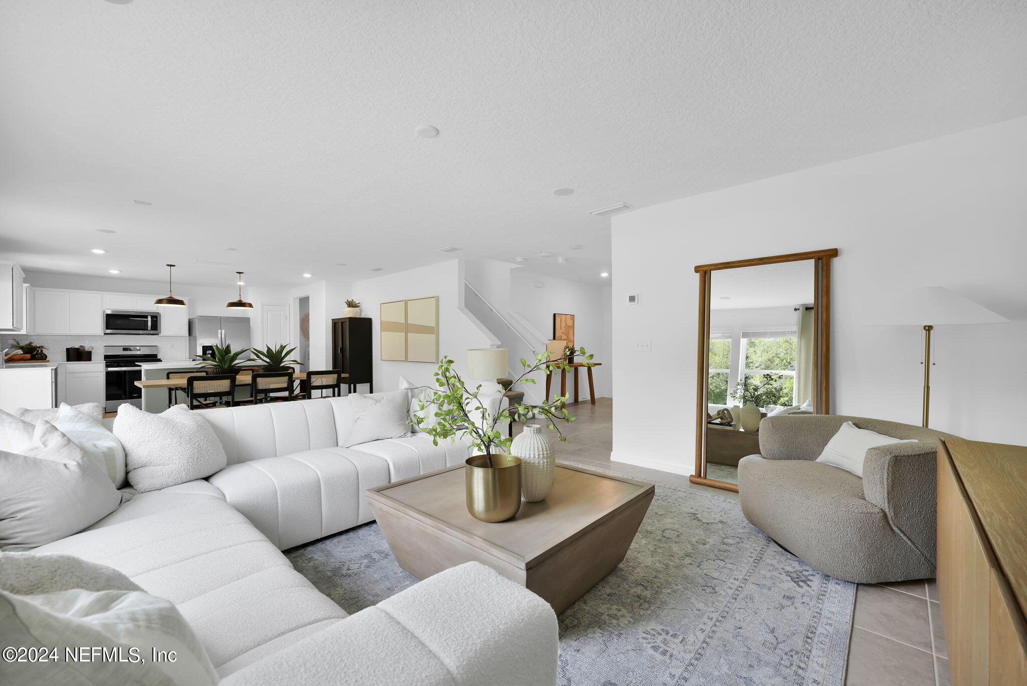 a living room with furniture white walls and a dining table with kitchen view