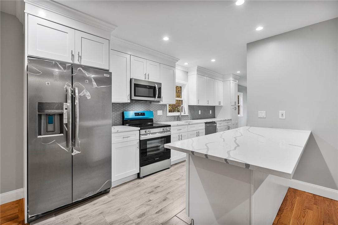 Kitchen featuring appliances with stainless steel finishes, white cabinets, and light hardwood / wood-style floors