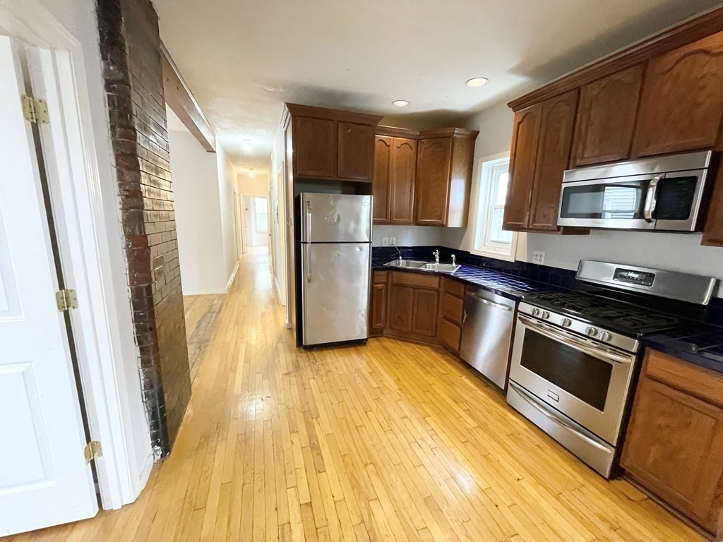 a kitchen with granite countertop a refrigerator a stove top oven a sink and dishwasher