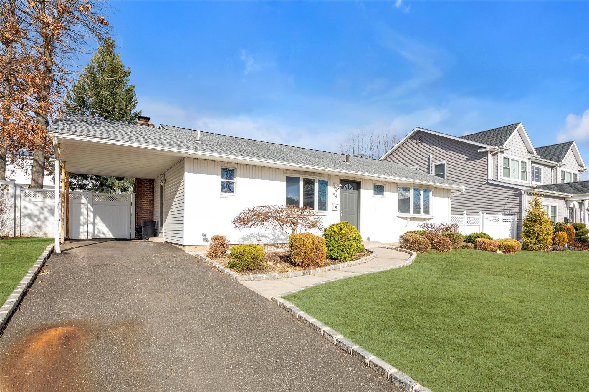 View of front facade with a carport and a front lawn